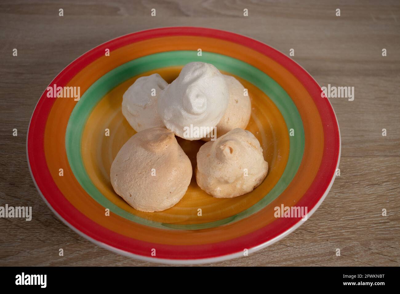 Meringues on colorful round plate. Traditional candy of meringue. Colorful bowl with meringues snacks. Stock Photo