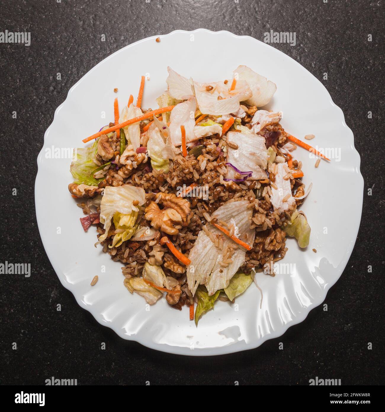 Salad with lettuce, carrot, onion, ham, pumpkin and sunflower seeds, brown rice, chicken, oil and salt Stock Photo