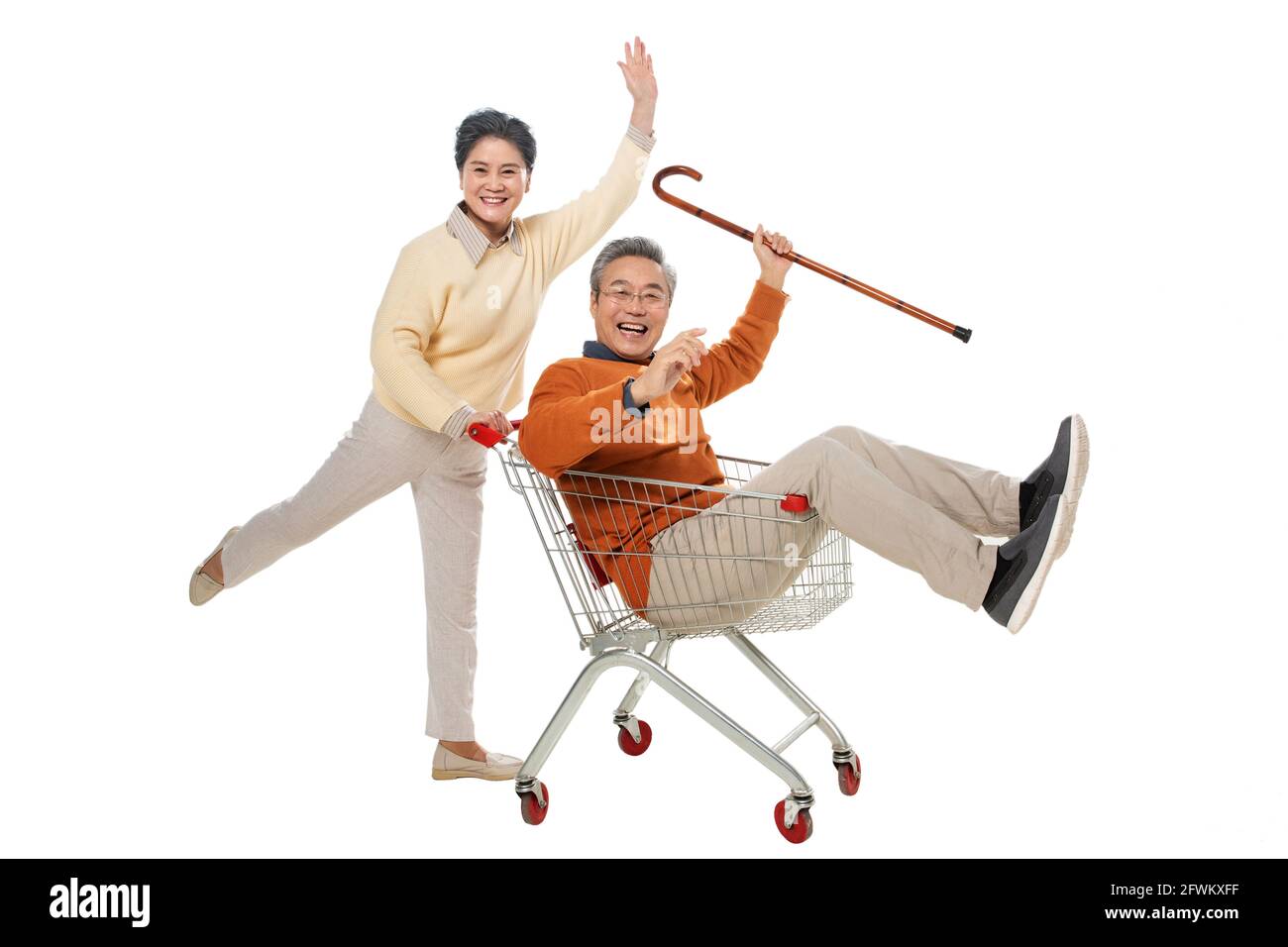 A happy old man pushes his wife sat in the shopping cart Stock Photo