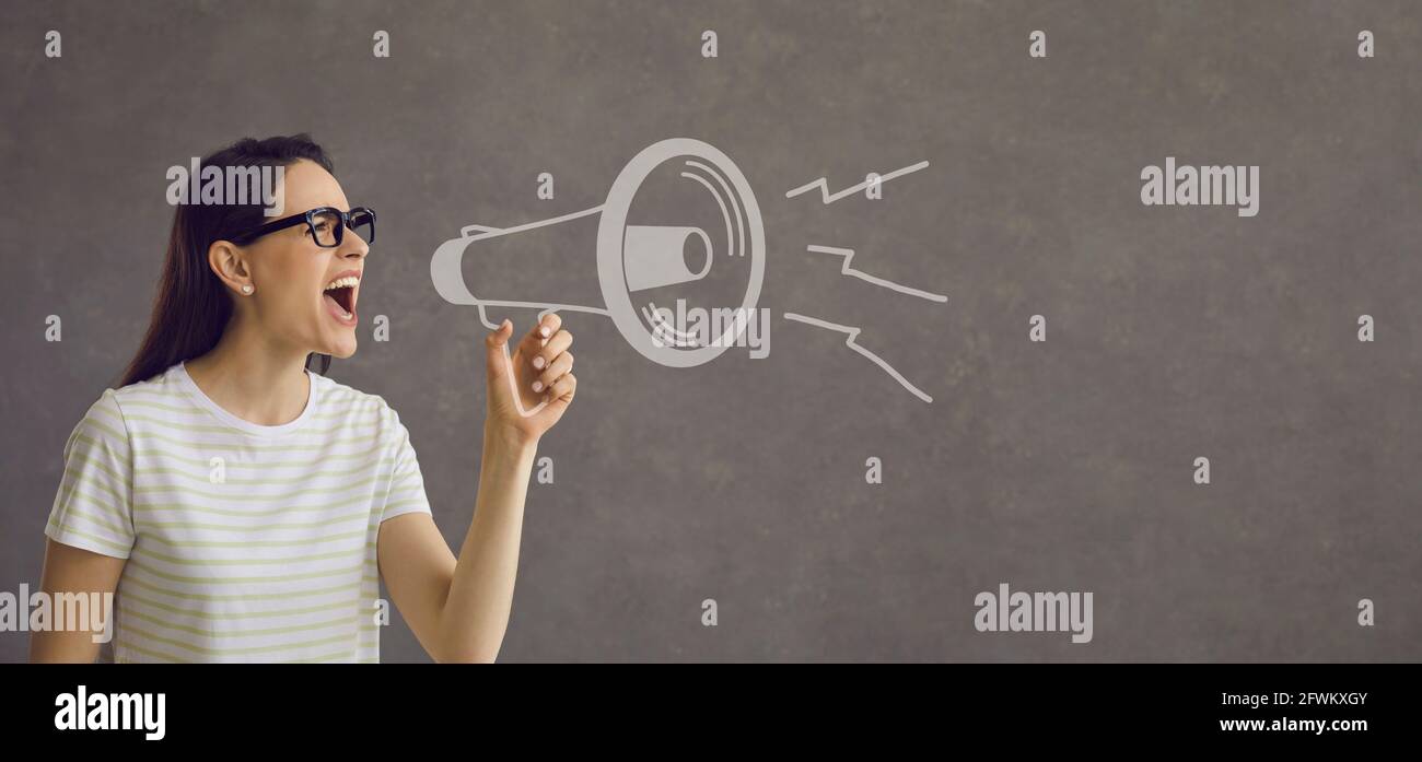 Serious woman draws attention to an important event by shouting loudly into a loudspeaker. Stock Photo