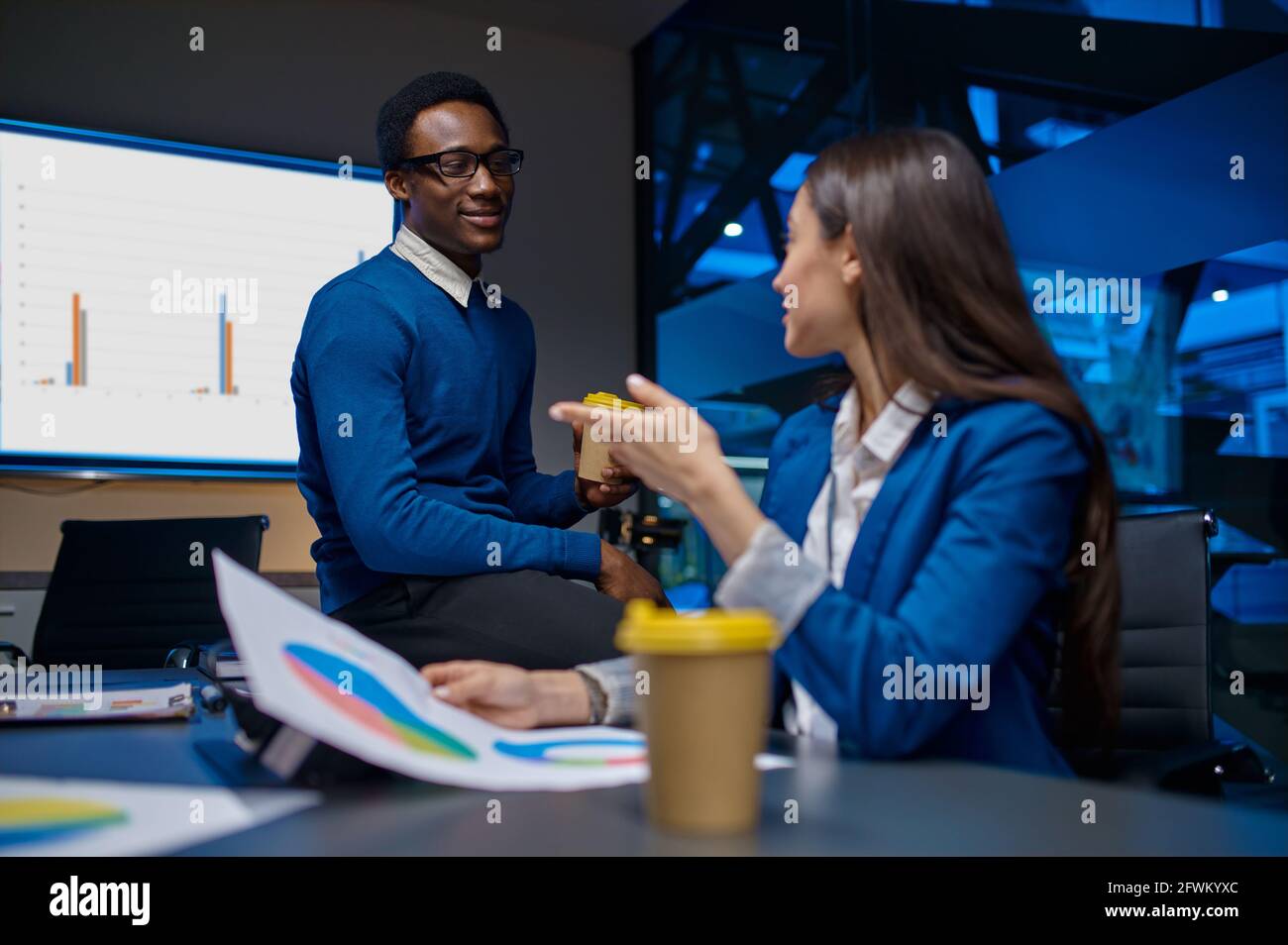 Two managers talks at the table in night office Stock Photo