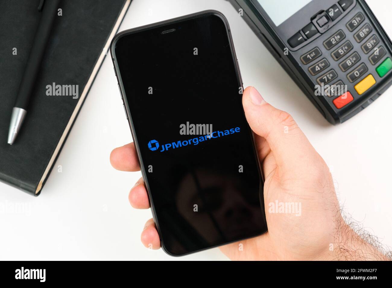 JP Morgan Chase bank logo on the smartphone screen in mans hand on the background of payment terminal, May 2021, San Francisco, USA Stock Photo