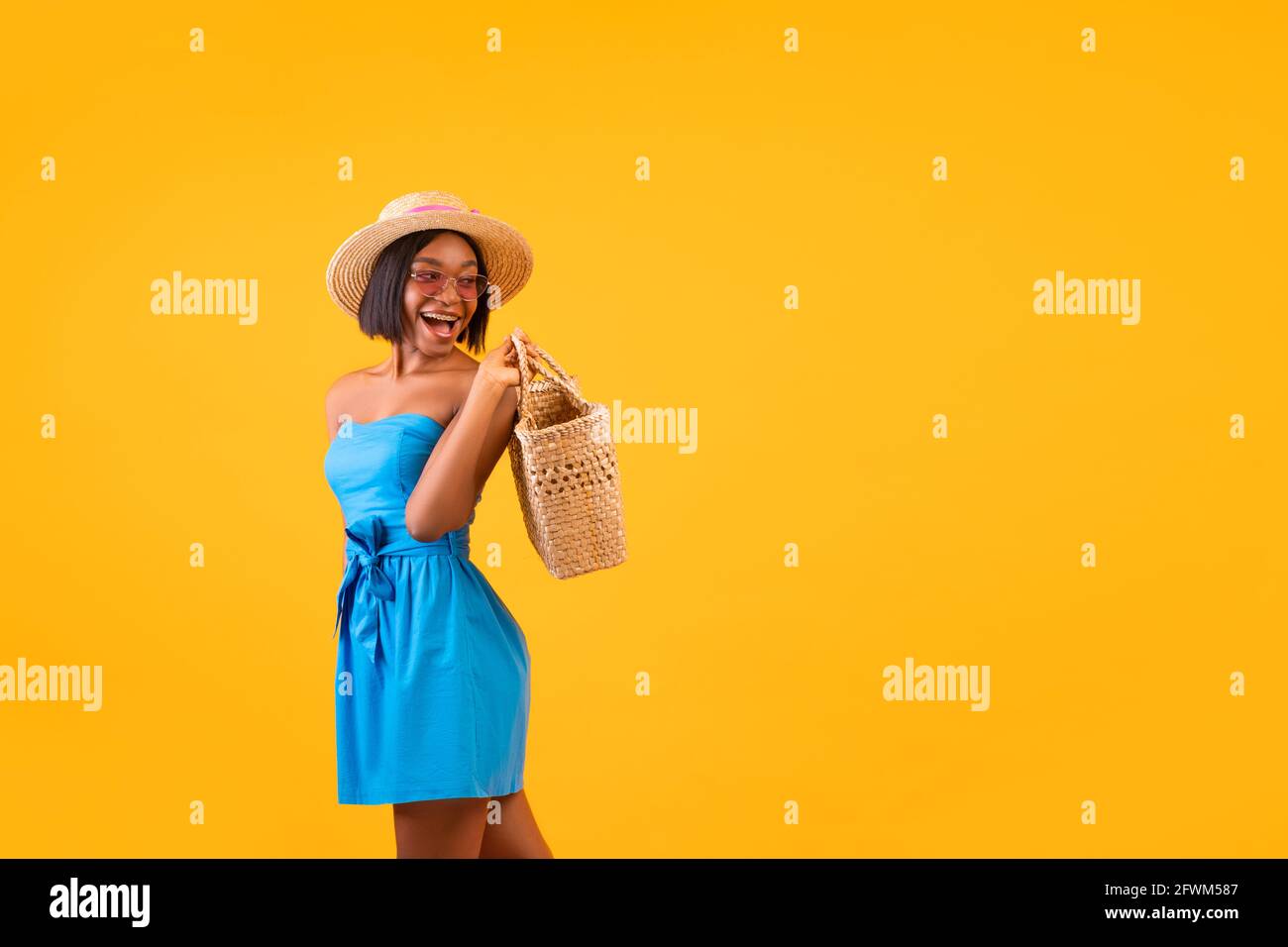 Portrait of black lady in summer outfit holding straw beach