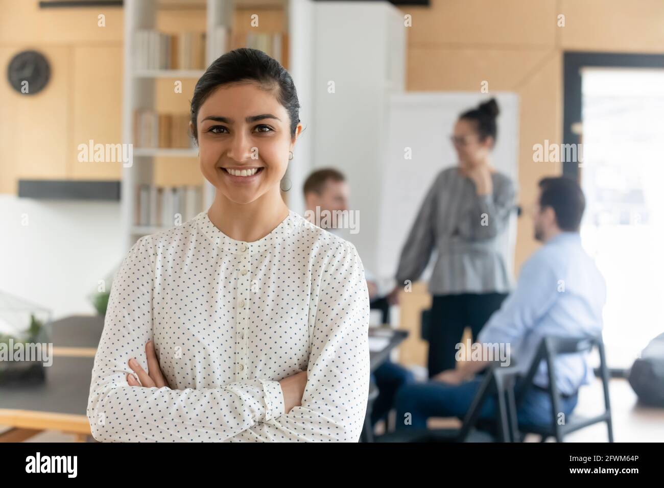 Head shot portrait smiling confident Indian businesswoman with arms crossed Stock Photo