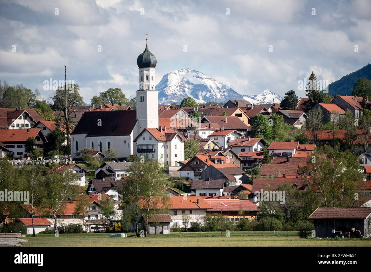 23 May 2021, Bavaria, Königsdorf: The snow-covered summit of the Juifen rises behind the church of Königsdorf. Photo: Matthias Balk/dpa Stock Photo