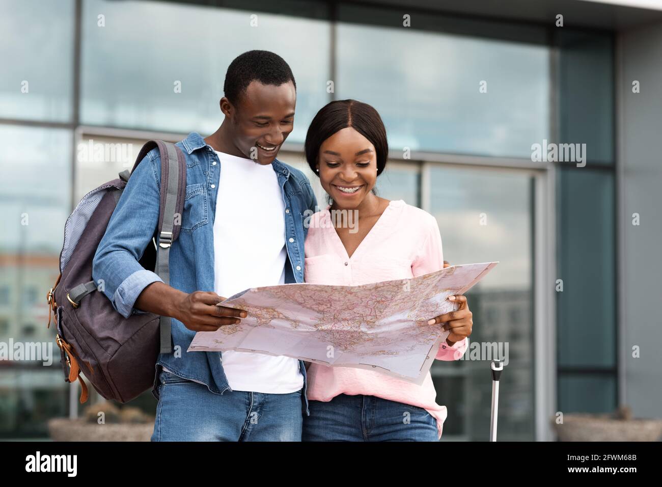 Two Happy Black Tourists Standing Near Airport, Checking City Map Stock Photo
