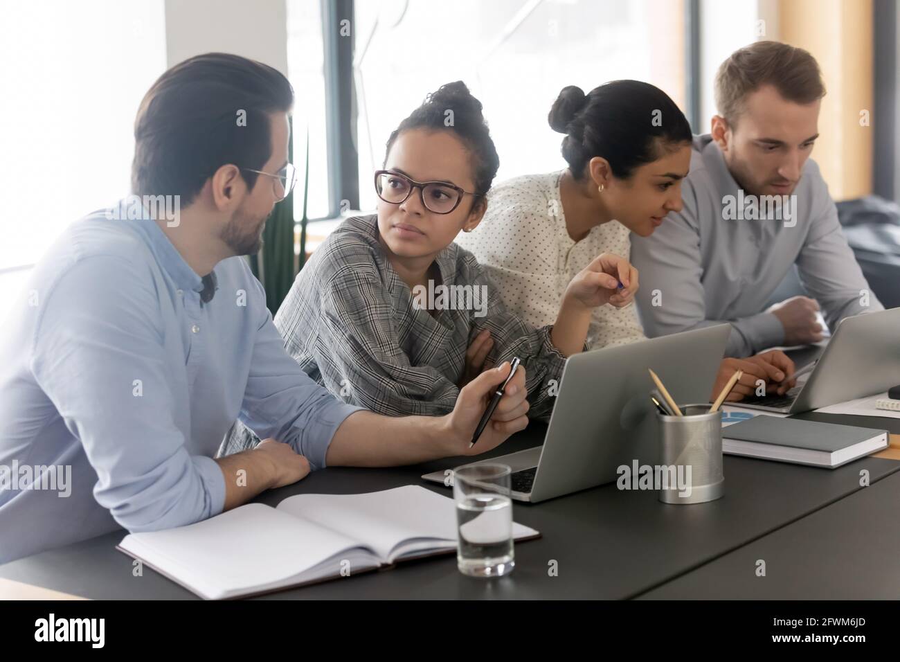 Diverse colleagues employees brainstorming, using laptops, working on project Stock Photo