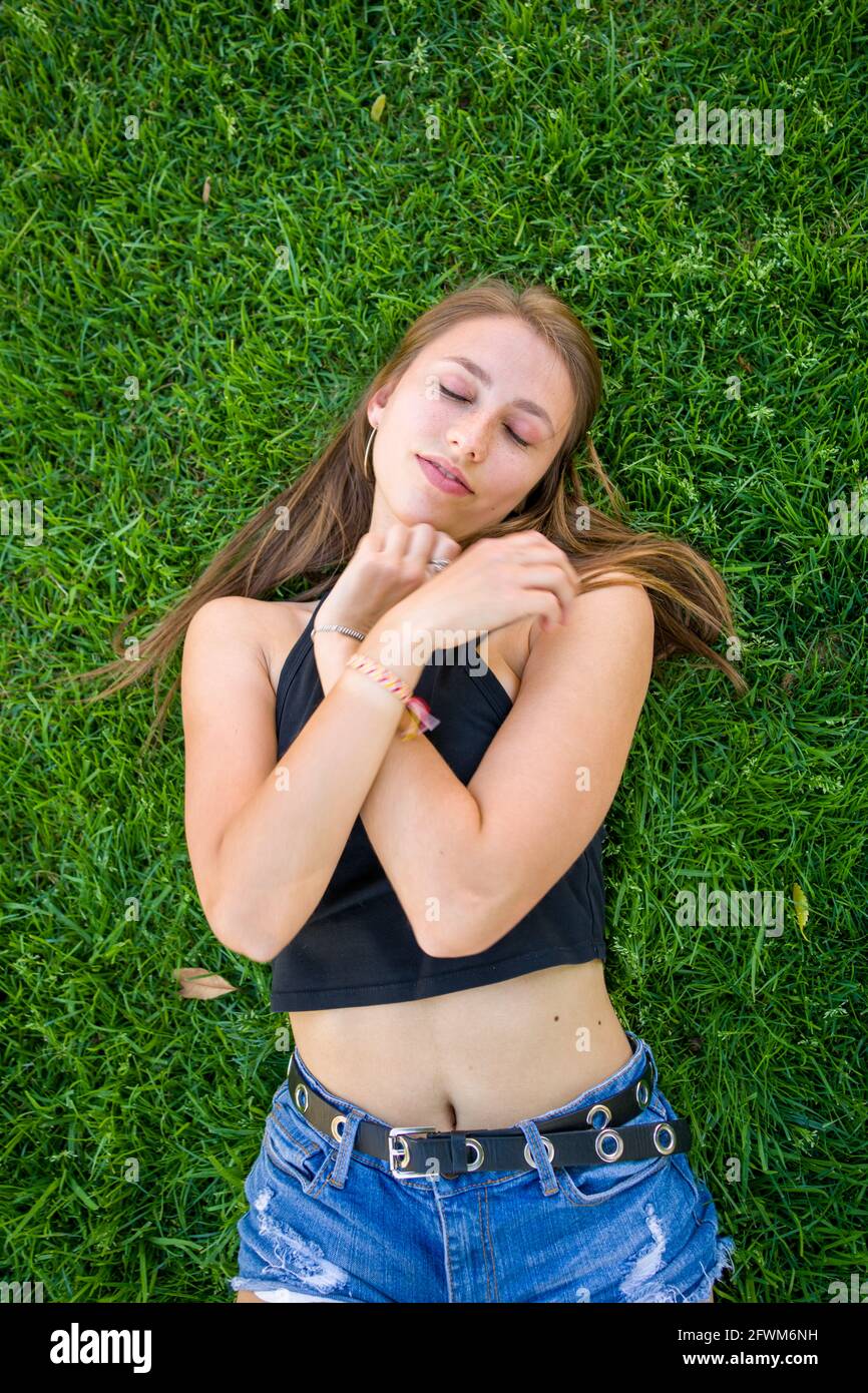 Young Woman Laying on Grass On University Campus Stock Photo