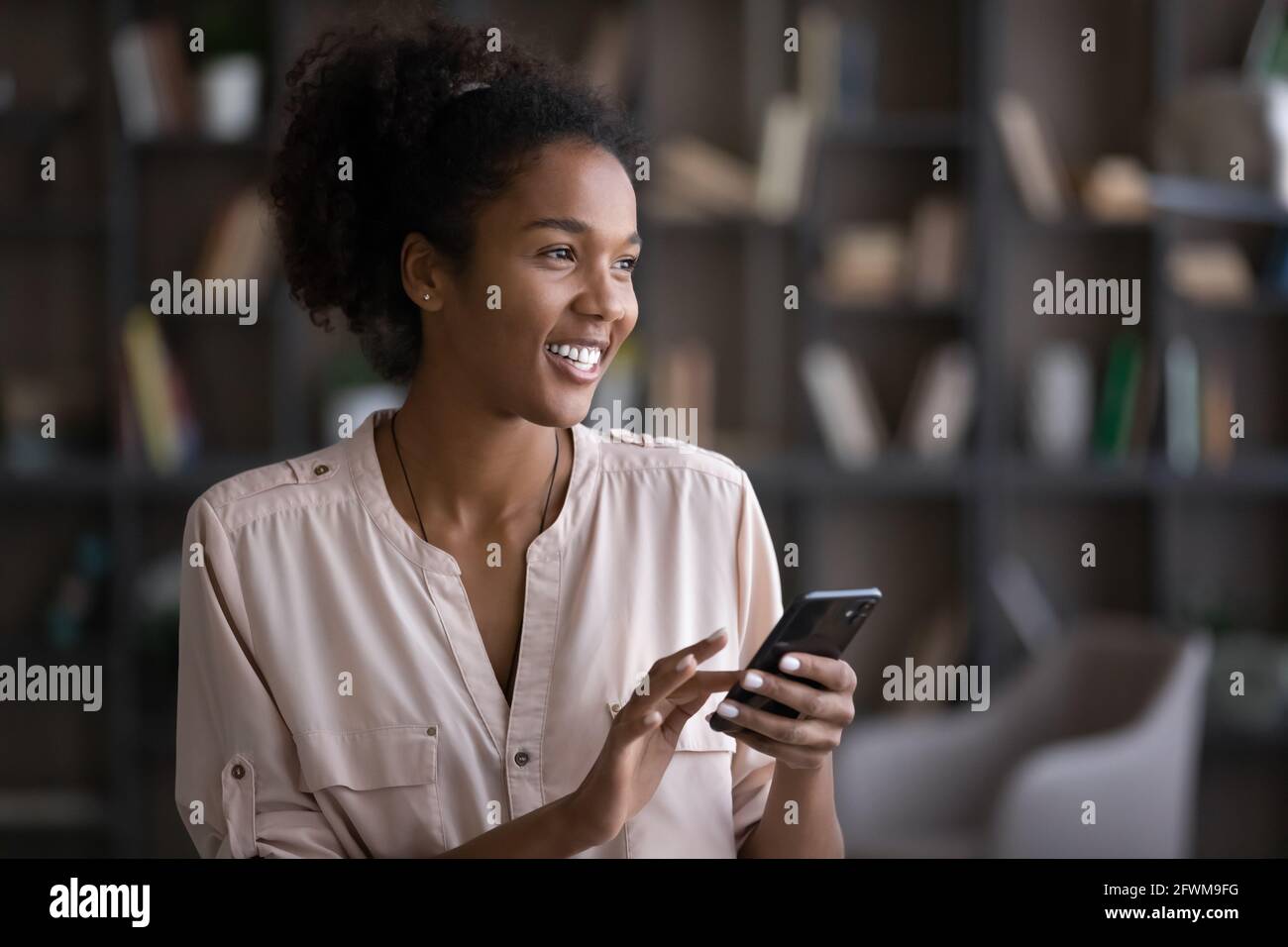 Happy young african american woman using smartphone. Stock Photo