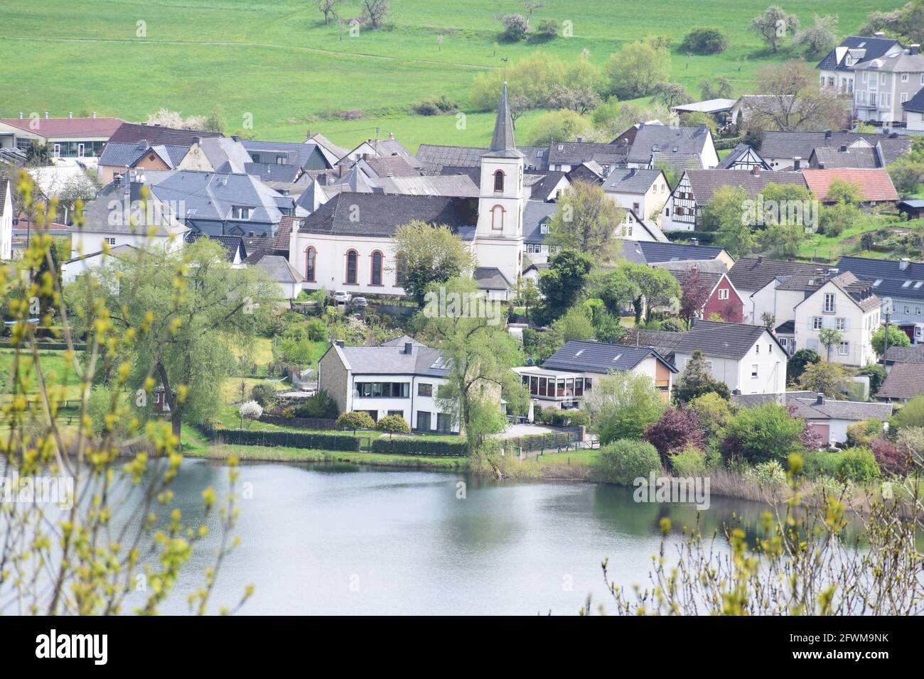 Schalkenmehrener Maar with the village in spring Stock Photo