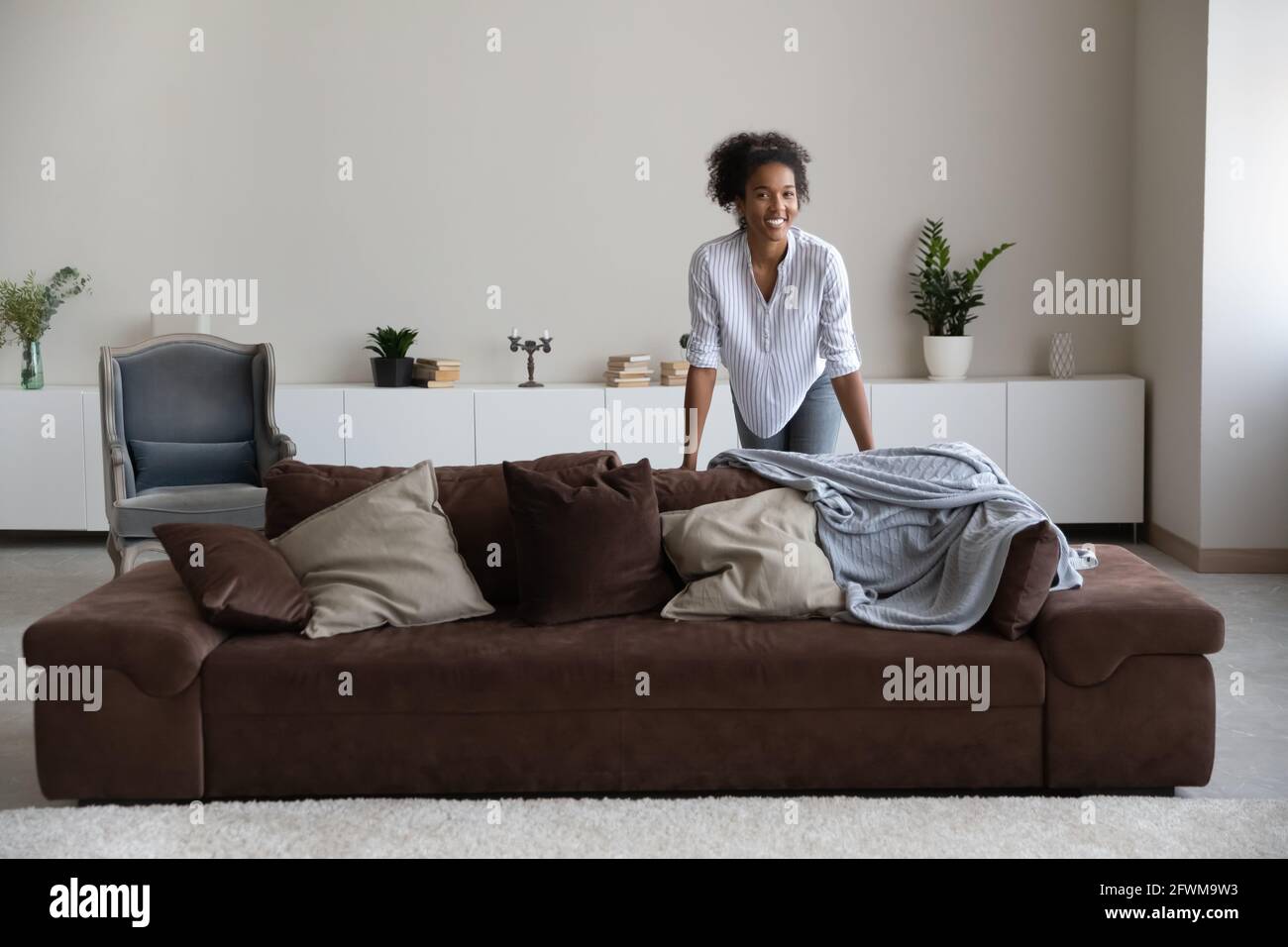 Joyful millennial african woman posing in modern stylish living room ...