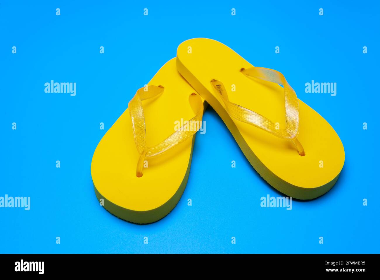 yellow flip flops on a blue background Stock Photo - Alamy