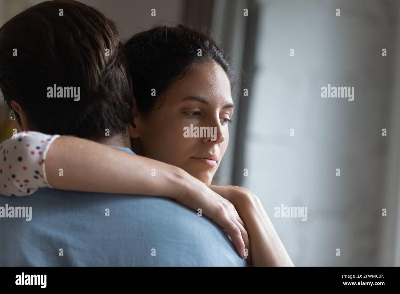 Unhappy thoughtful young woman cuddling husband, feeling stressed after conflict, Stock Photo