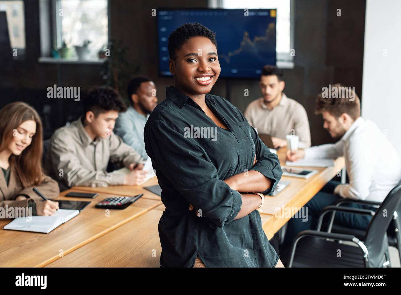 African American businesswoman sitting on desk and posing Stock Photo ...