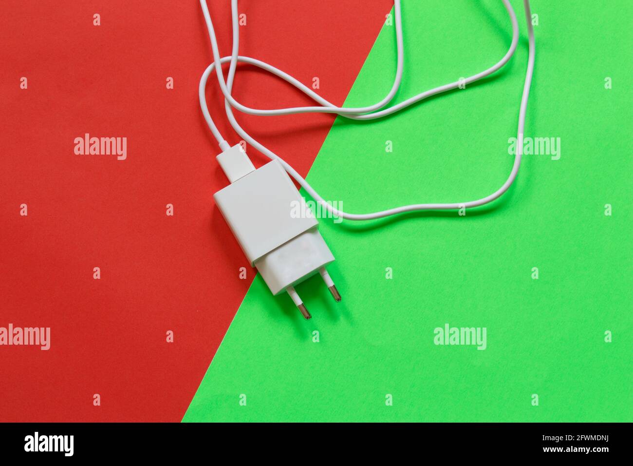 White phone charger isolated on half red half green background