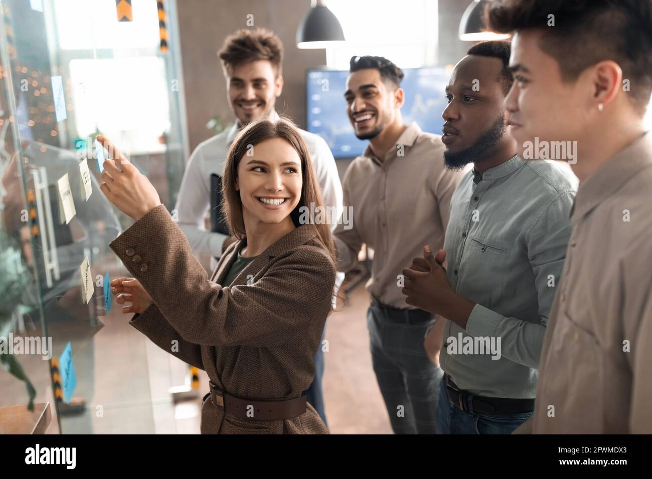 Colleagues having meeting using sticky notes on glass wall Stock Photo