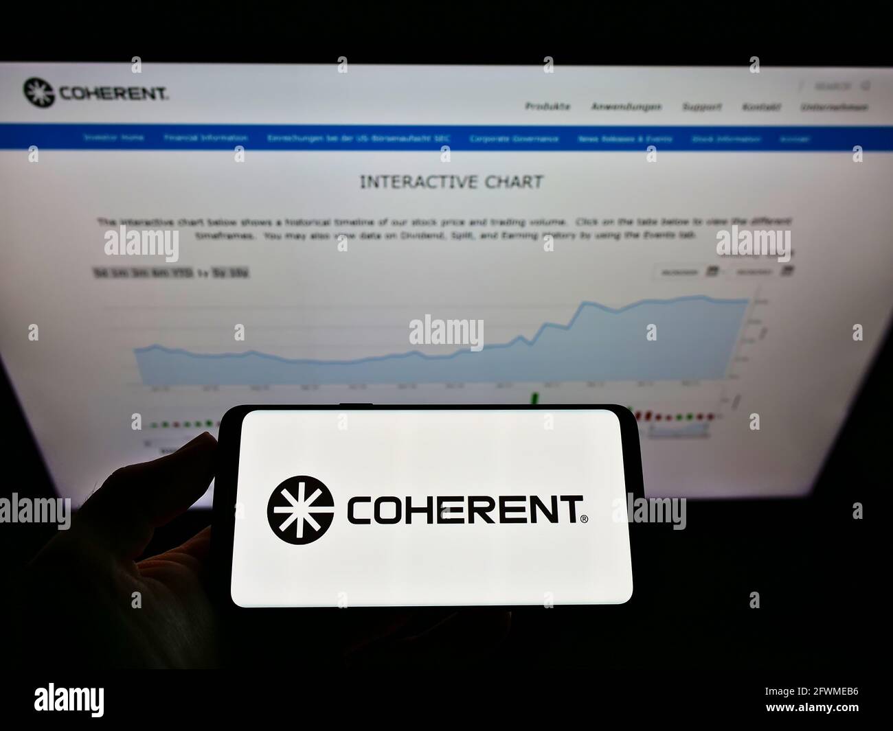Person holding cellphone with business logo of US laser manufacturer Coherent Inc. on screen in front of company website. Focus on phone display. Stock Photo