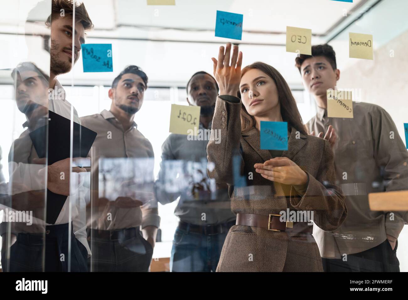 Colleagues having meeting using sticky notes on glass wall Stock Photo