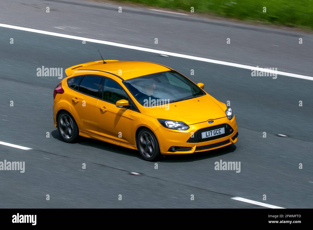 2013 yellow Ford Focus 4dr 1999cc saloon car driving on the M6 motorway near Preston in Lancashire, UK Stock Photo