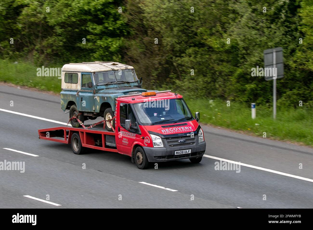 2008 Ford Transit 100 T350ef Rwd dropside truck, carrying barn find, driving on the M6 motorway near Preston in Lancashire, UK Stock Photo