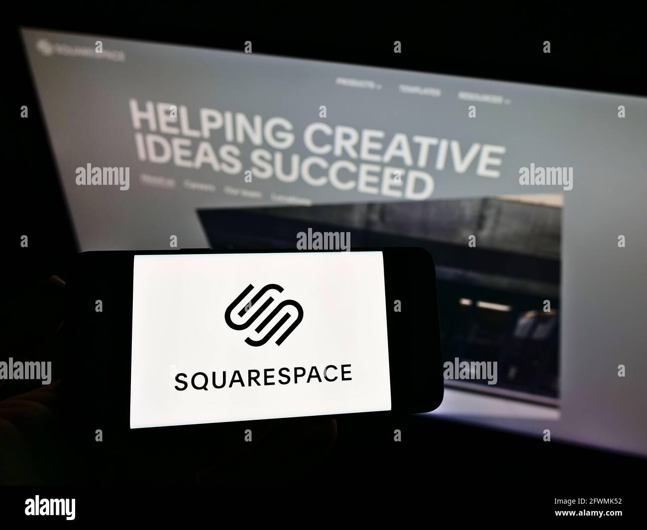 Person holding smartphone with logo of US hosting platform company Squarespace Inc. on screen in front of website. Focus on phone display. Stock Photo
