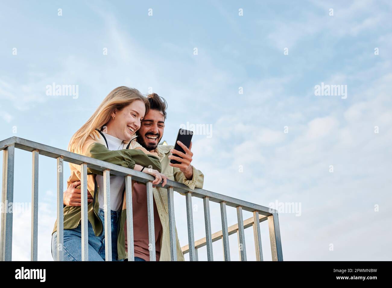 Young multiracial couple smiles while they are looking at a phone Stock Photo