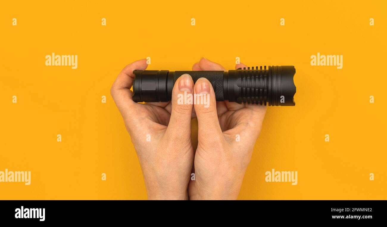 Banner hand hold flashlight on office desk yellow orange background, top view, workspace concept with copy space Stock Photo