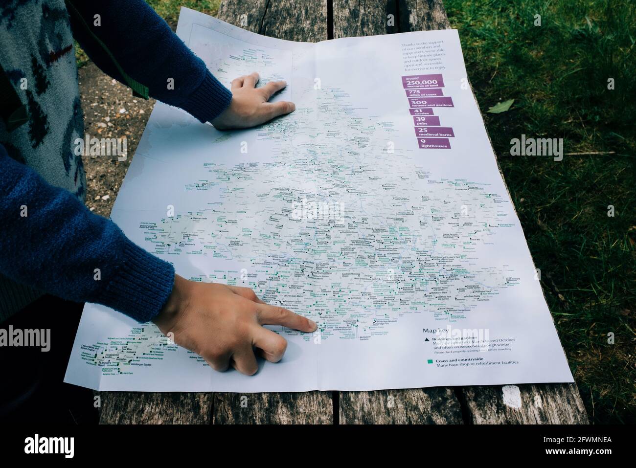 child pointing at a map of England whilst outdoors exploring Stock Photo
