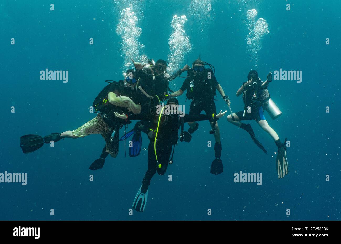 group of divers performing the mandatory safety stop while ascending Stock Photo