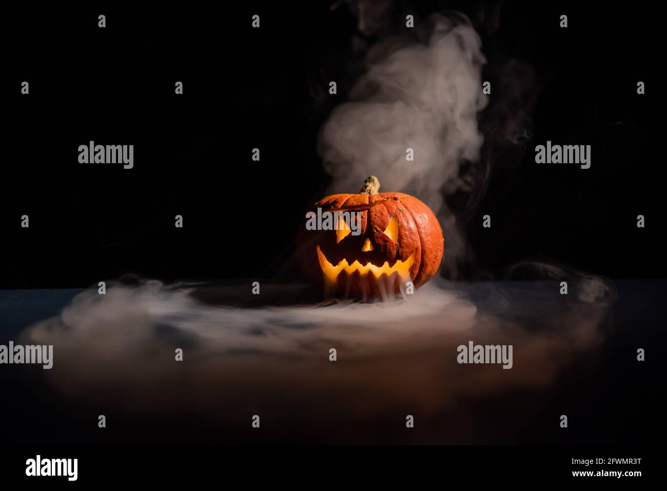 Halloween, orange pumpkin with a scary luminous face on a dark ...