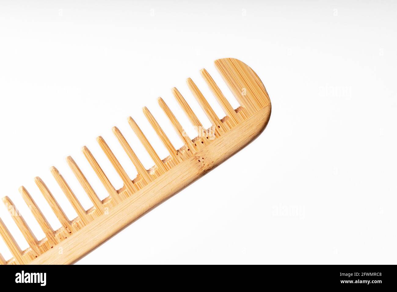 bamboo wood comb diagonally on white background with soft lighting ...