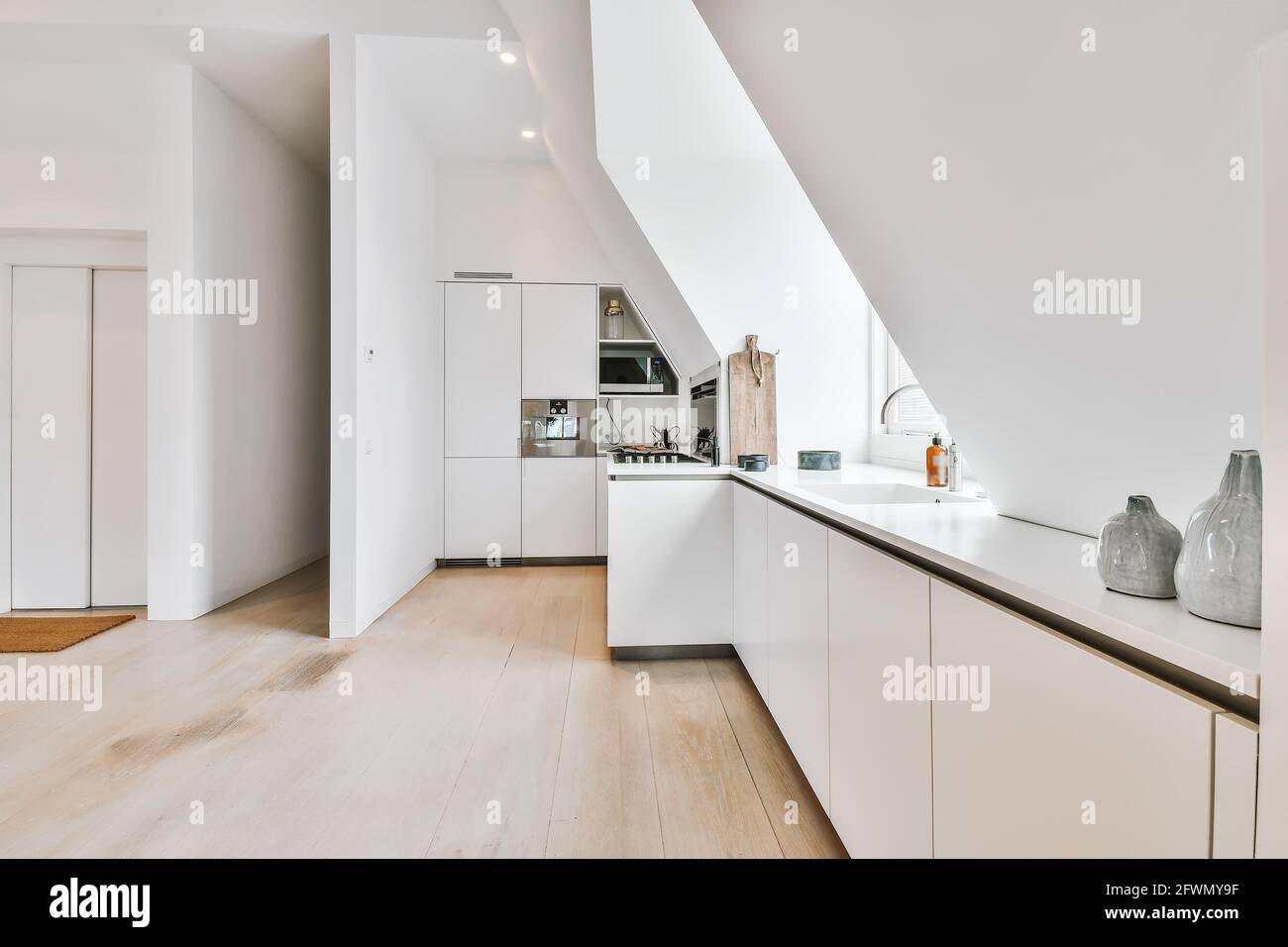 Contemporary kitchen interior with white and shiny appliances in apartment with mansard