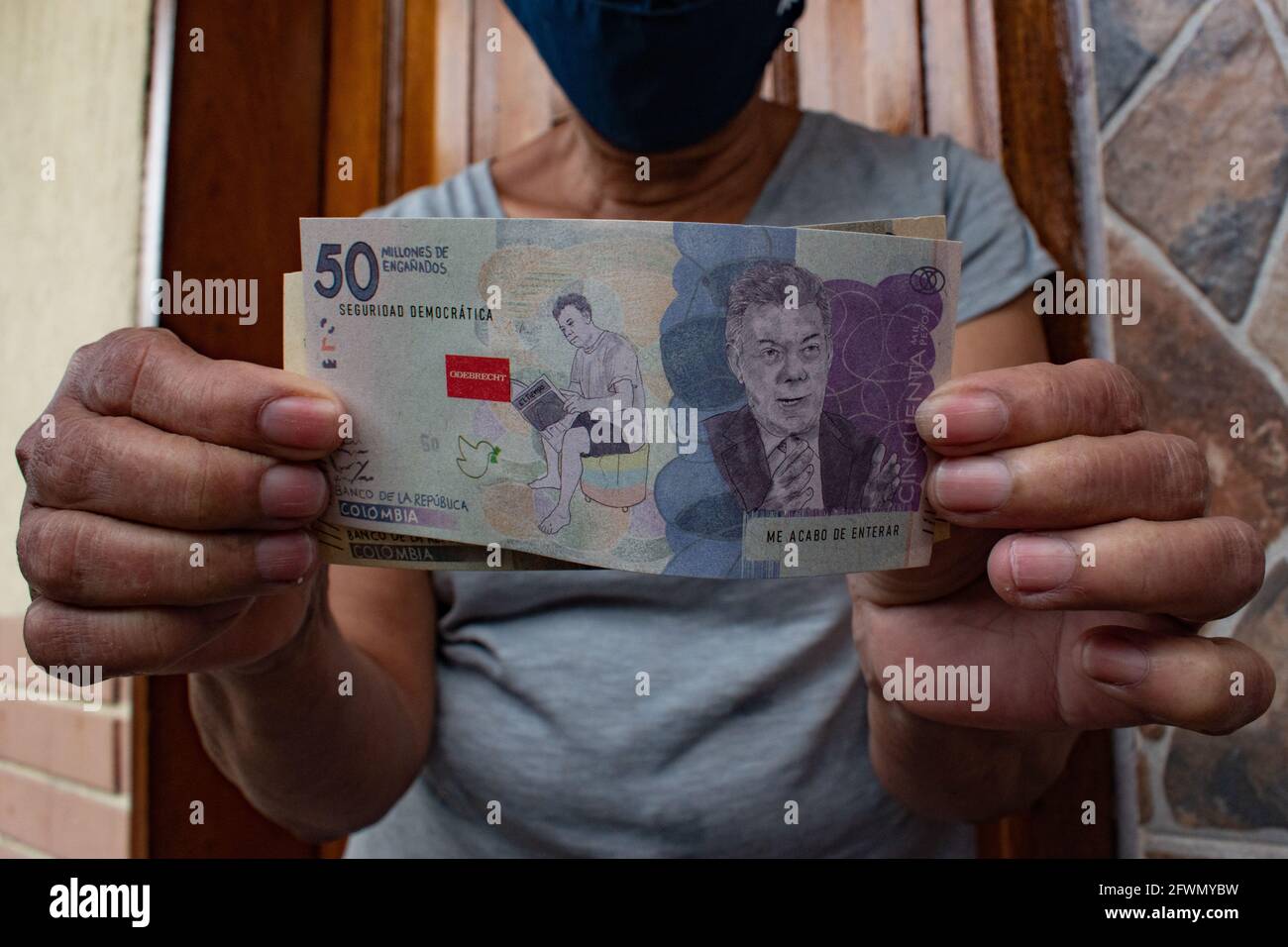 Medellin, Antioquia, Colombia. 22nd May, 2021. A demonstrator holds a fake fifty thousand pesos note with the image of former president Juan Manuel Santos and the logo of ODEBRECHT as clashes and riots evolve in Medellin, Colombia after demonstrators and riot police (ESMAD) during a demonstration that escalated to clashes after security cameras and commerce were affected by the protest. In Medellin, Antioquia, Colombia on 22, 2021. Credit: Miyer Juana/LongVisual/ZUMA Wire/Alamy Live News Stock Photo