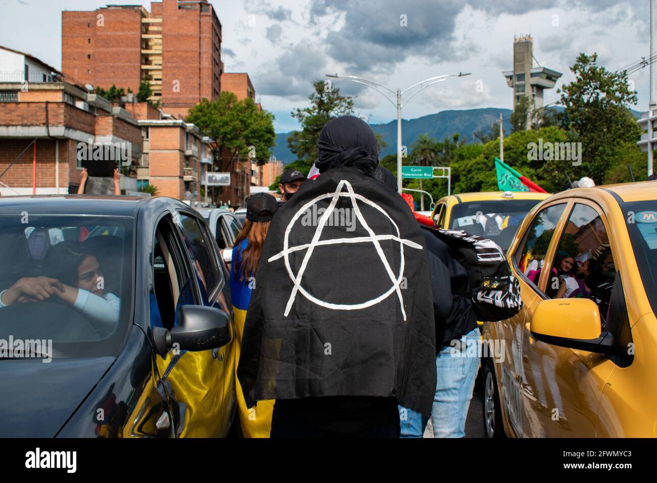 Medellin, Antioquia, Colombia. 22nd May, 2021. A demonstrator with an Anarchy logo flag walks in between cars as clashes and riots evolve in Medellin, Colombia after demonstrators and riot police (ESMAD) during a demonstration that escalated to clashes after security cameras and commerce were affected by the protest. In Medellin, Antioquia, Colombia on 22, 2021. Credit: Miyer Juana/LongVisual/ZUMA Wire/Alamy Live News Stock Photo