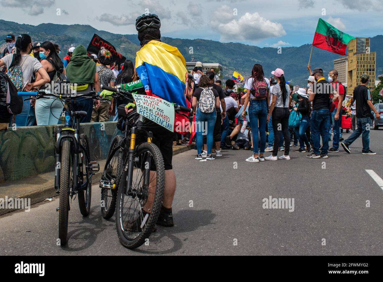 A demonstrator has a colombian flag wraped on his neck as he has a message in his bike that reads 'The protests gave us a voice, the power of voting will give us a change, resistance! As clashes and riots evolve in Medellin, Colombia after demonstrators and riot police (ESMAD) during a demonstration that escalated to clashes after security cameras and commerce were affected by the protest. In Medellin, Antioquia, Colombia on 22, 2021. Stock Photo