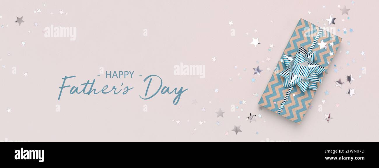 Happy Father's Day greeting card. Blue gift and confetti on beige background. Web banner, copy space. Stock Photo
