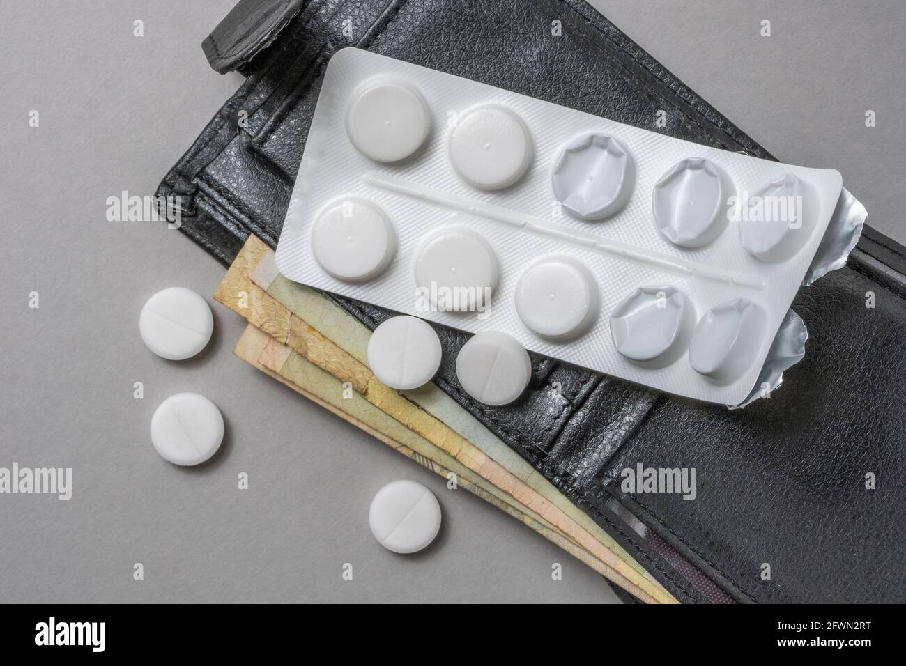 Black wallet with money on it pills are on the table. Stock Photo