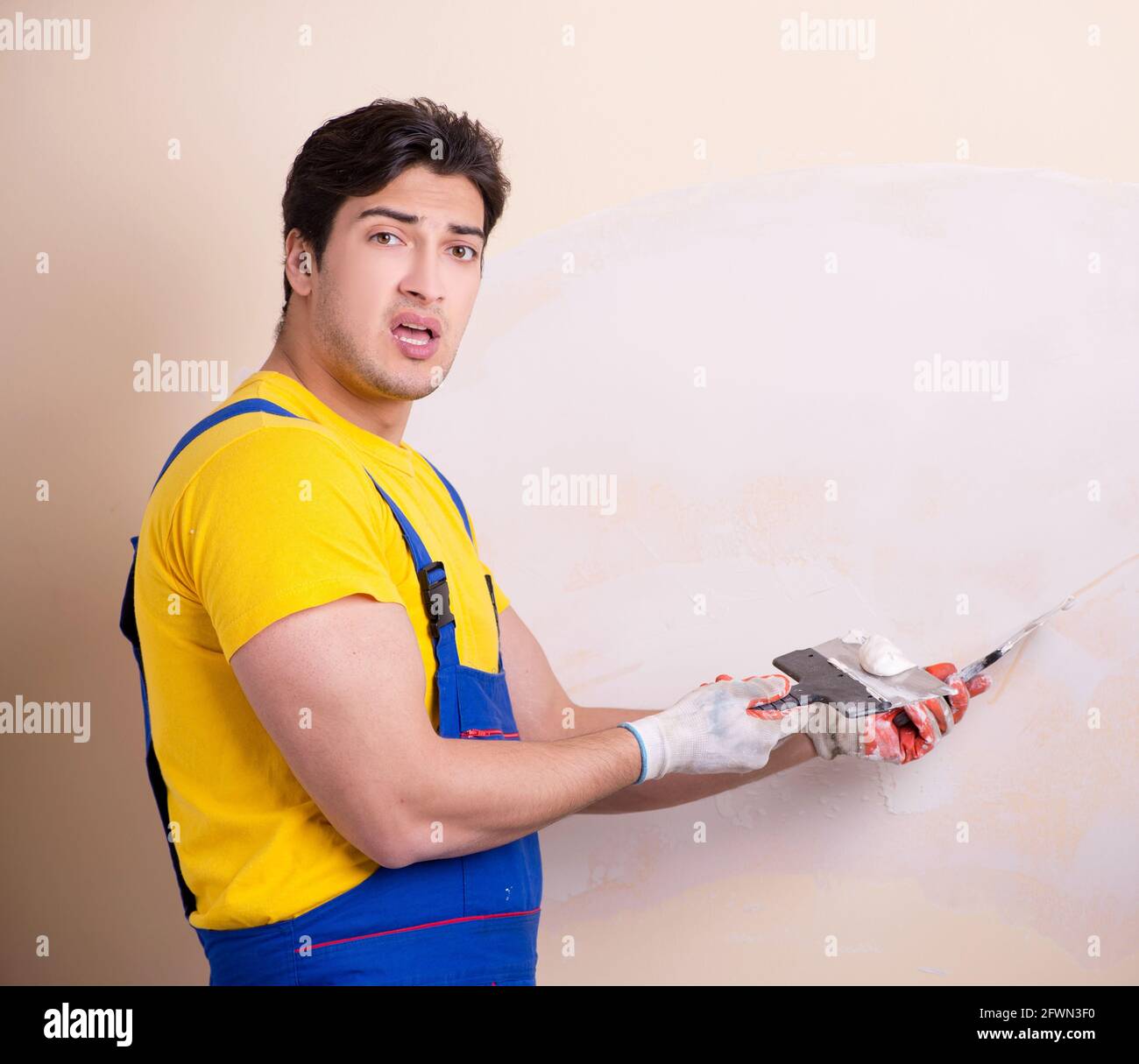 The young contractor employee applying plaster on wall Stock Photo