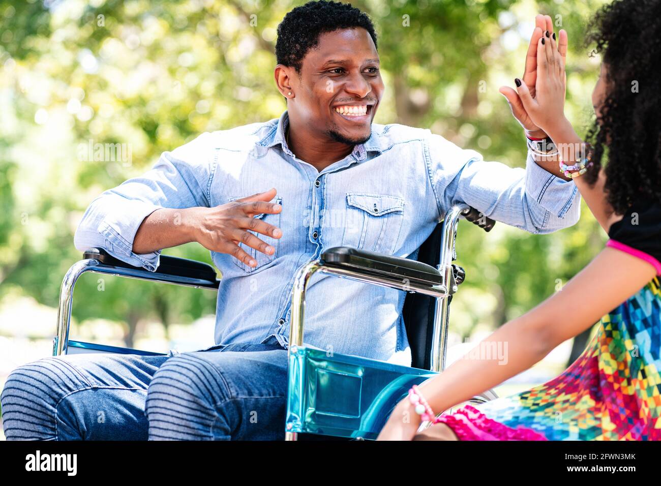 Man in a wheelchair at the park with his daughter Stock Photo - Alamy