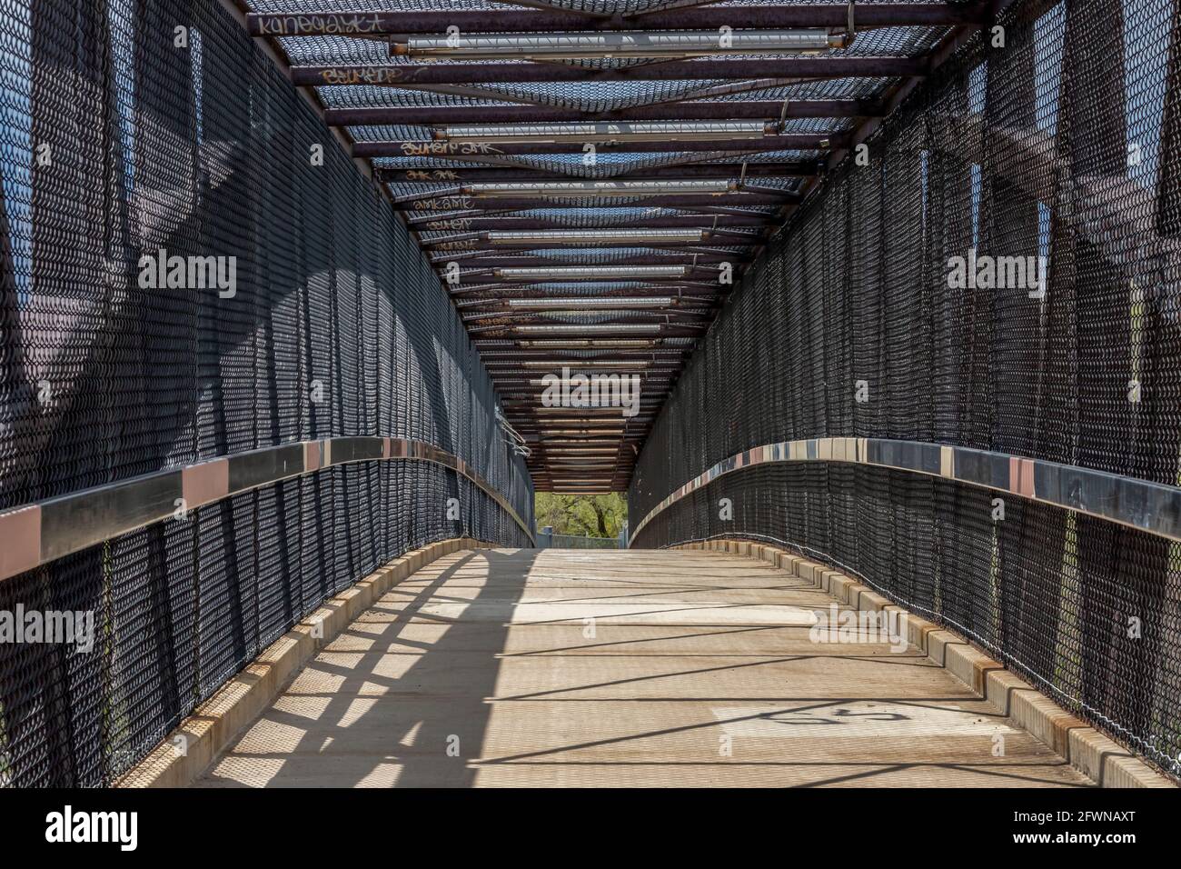 Inside of a modern overhead pedestrian bridge over a highway on a sunny day. Stock Photo