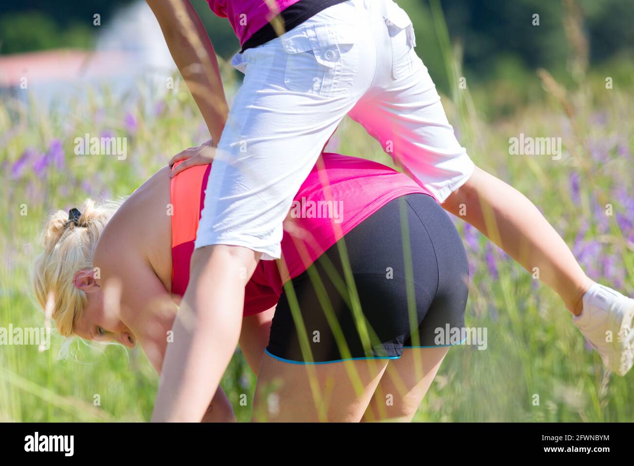Girl jump outside in field over woman while leapfrogging Stock Photo