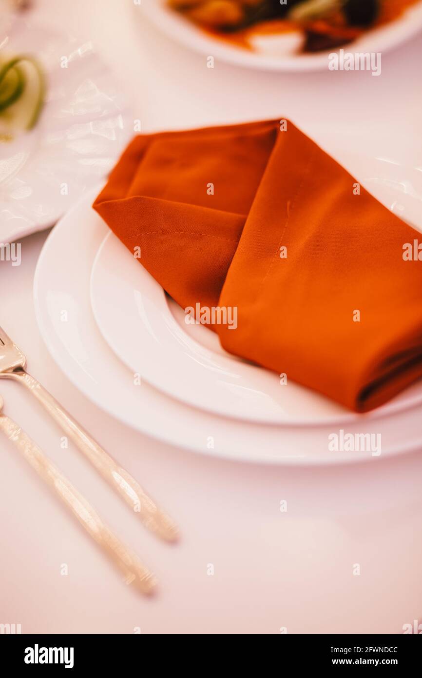 Table setting, red napkin lies on a white plate. Stock Photo