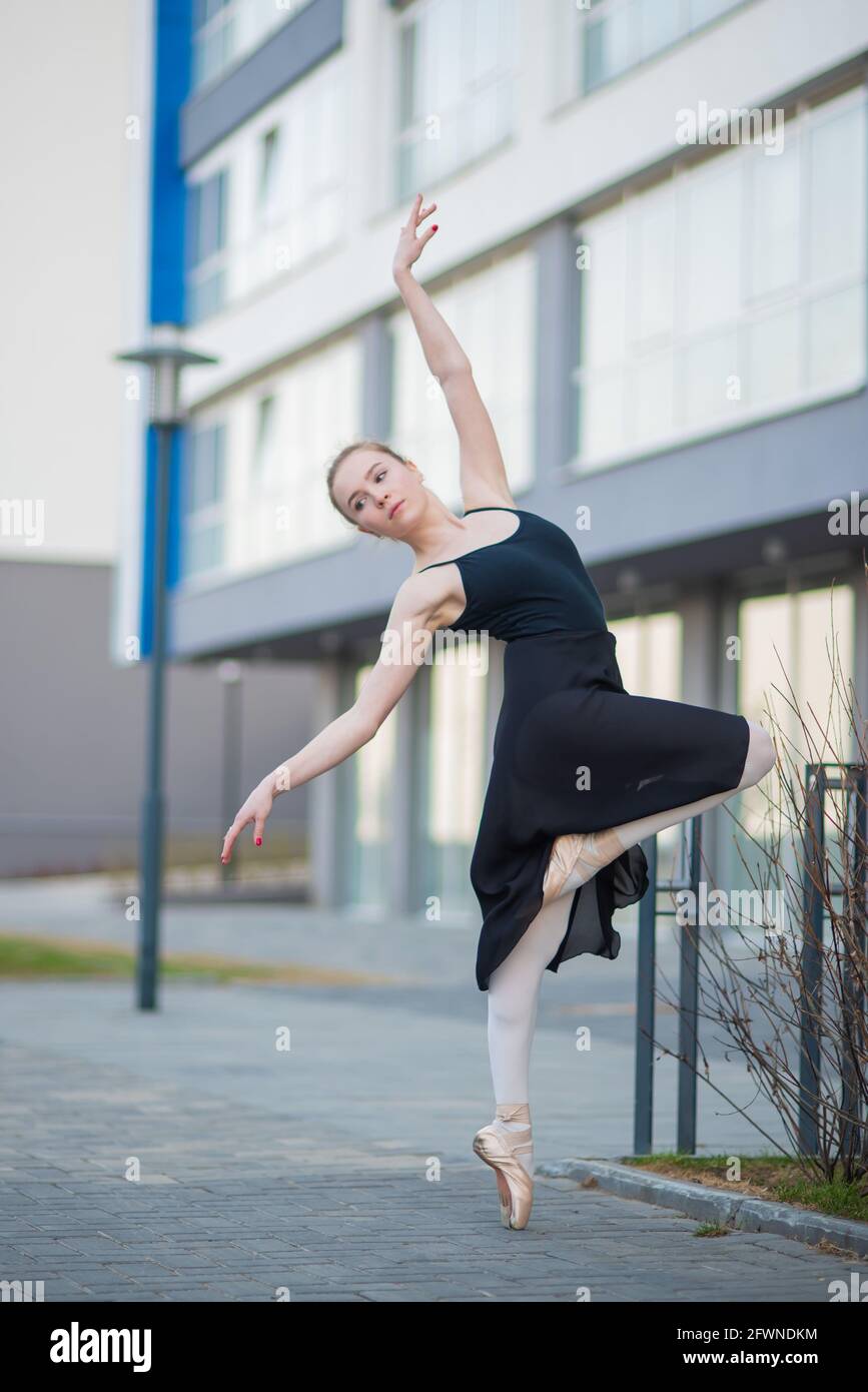brugt amerikansk dollar Effektivitet Ballerina in a tutu posing against the backdrop of a residential building.  Beautiful young woman in black dress and pointe shoes dancing ballet Stock  Photo - Alamy
