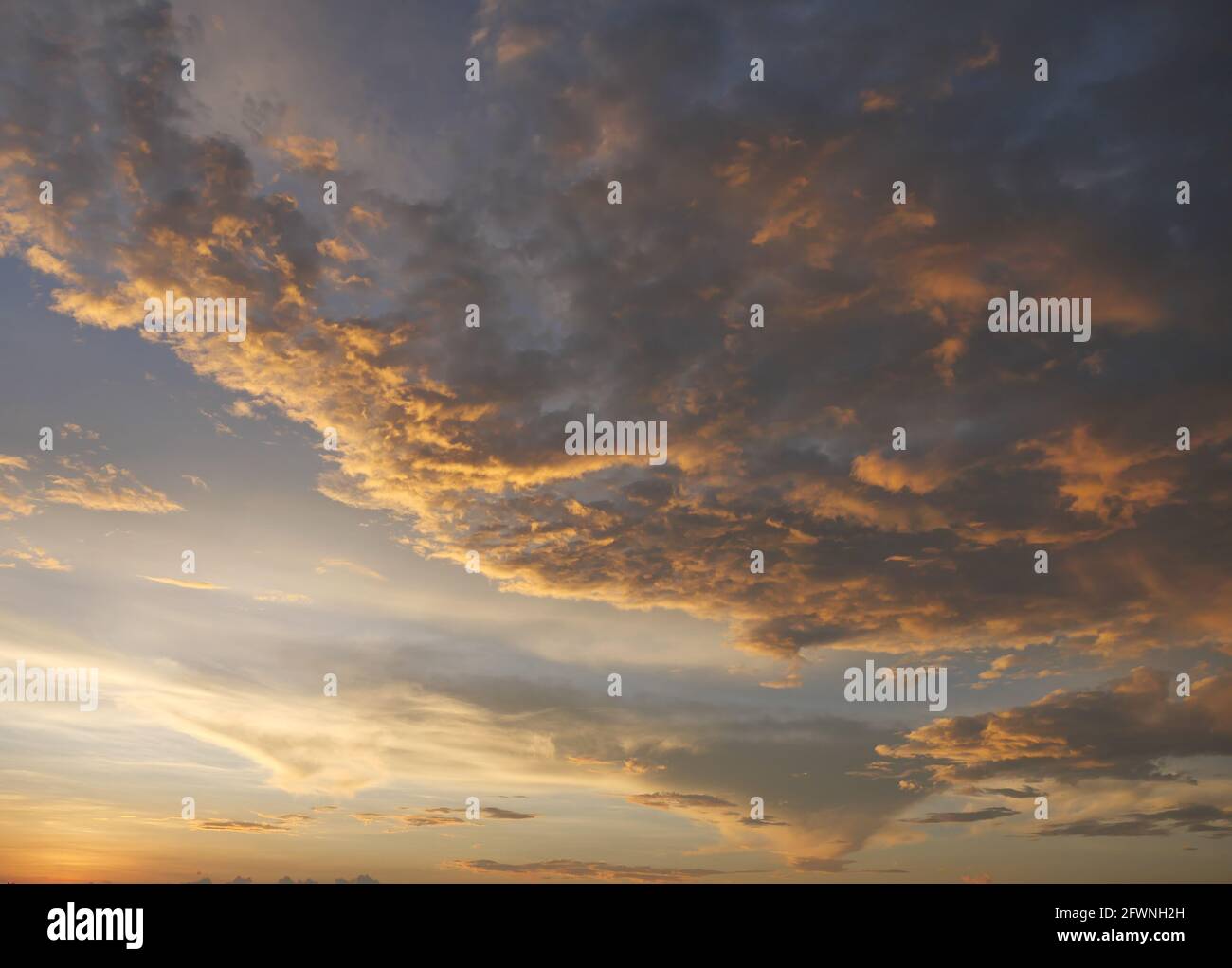 Gold color cloud and blue sky in magic hour at sunset, The horizon began to turn orange with purple clouds at night, Dramatic cloudscape area Stock Photo