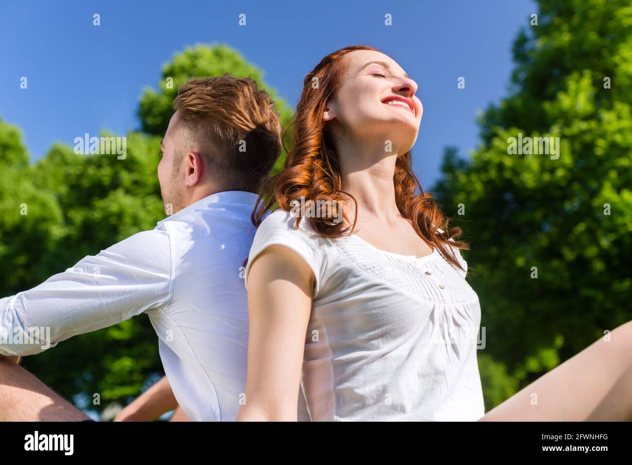 Couple in love sitting on park lawn enjoying sun Stock Photo - Alamy