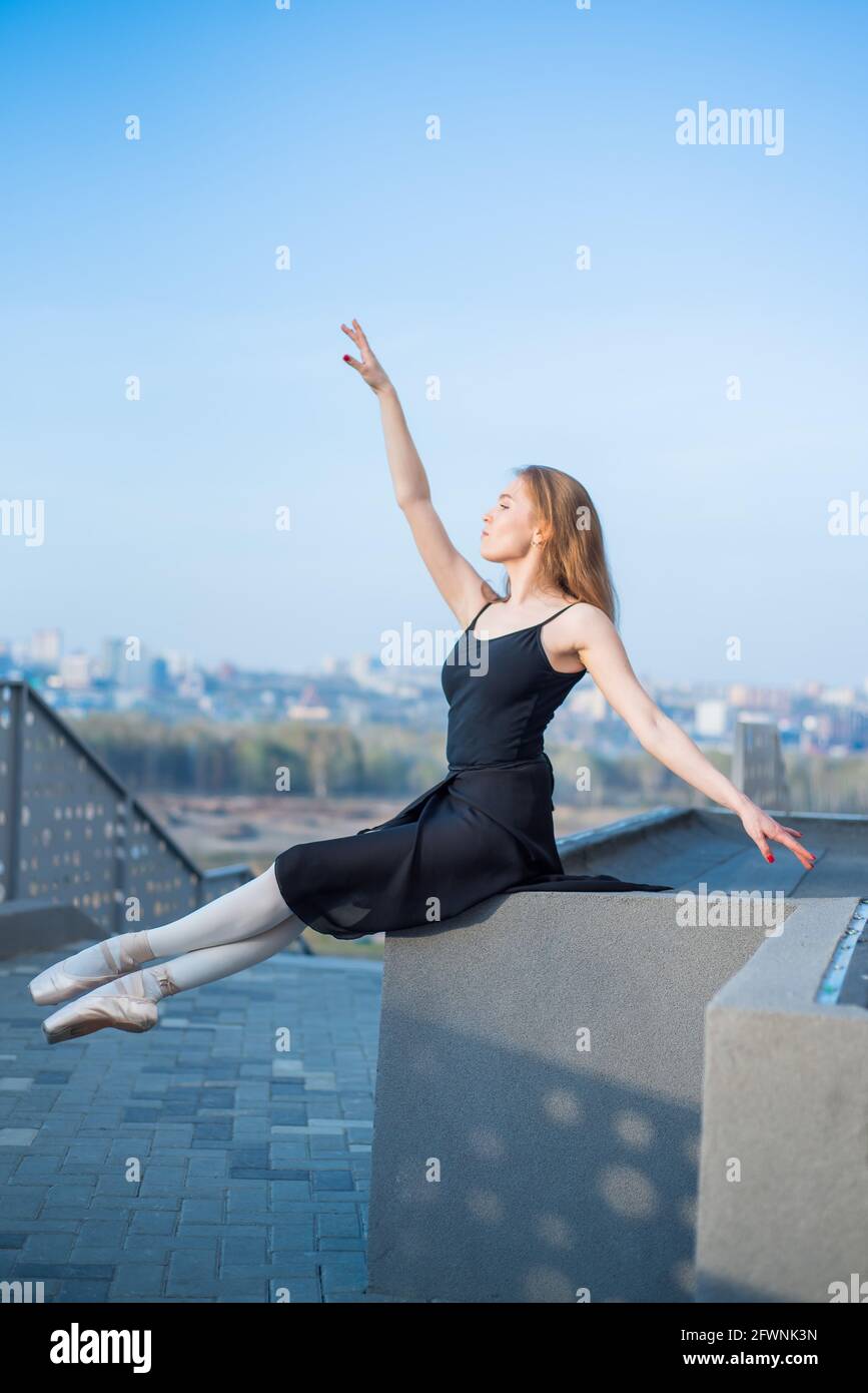 Ballerina in tutu posing sitting. Beautiful young woman in black dress ...
