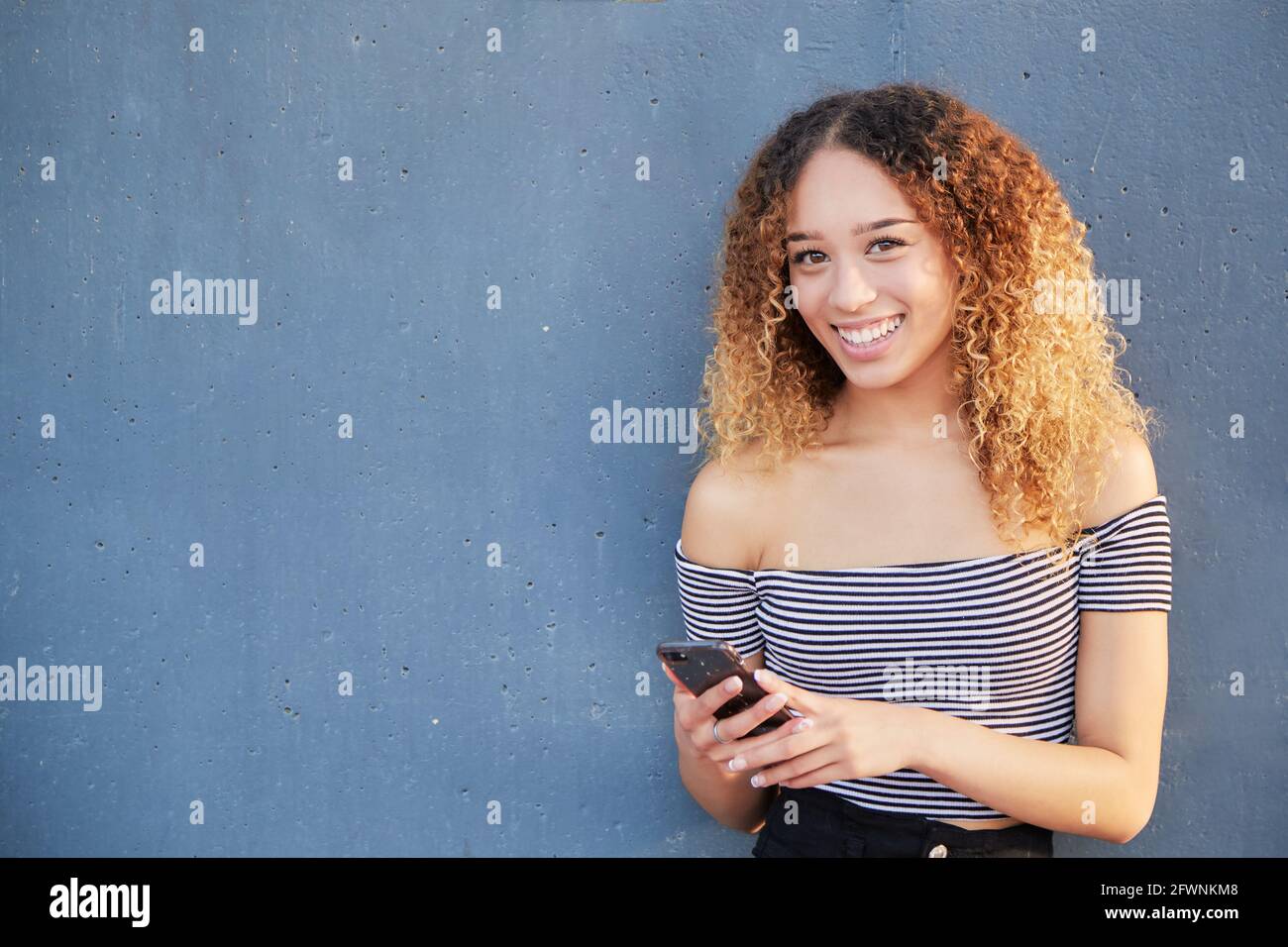 Smiling teenage latina girl holding smart phone using mobile app ...