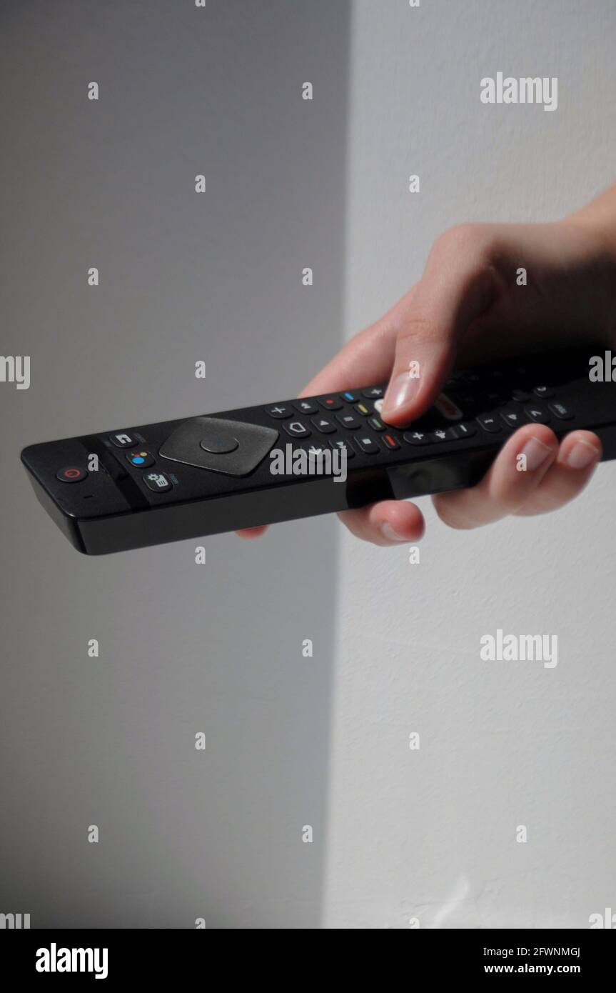 Hand with black tv remote control on white background Stock Photo