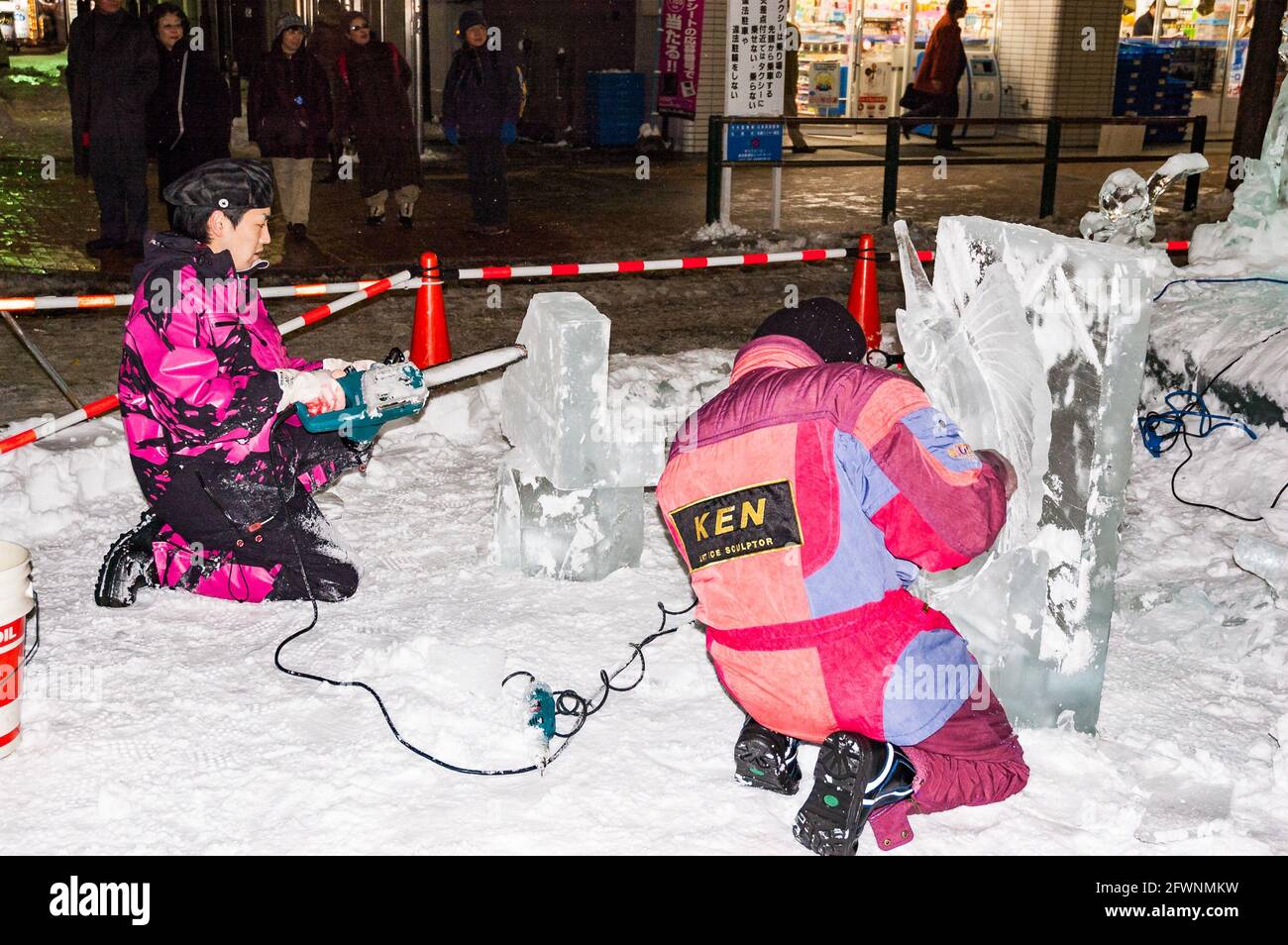 Two sculptors use chainsaws to sculpt art work out of blocks of ice at the Susukino Ice Festival, part of the Sapporo Snow Festival celebrations in Ja Stock Photo
