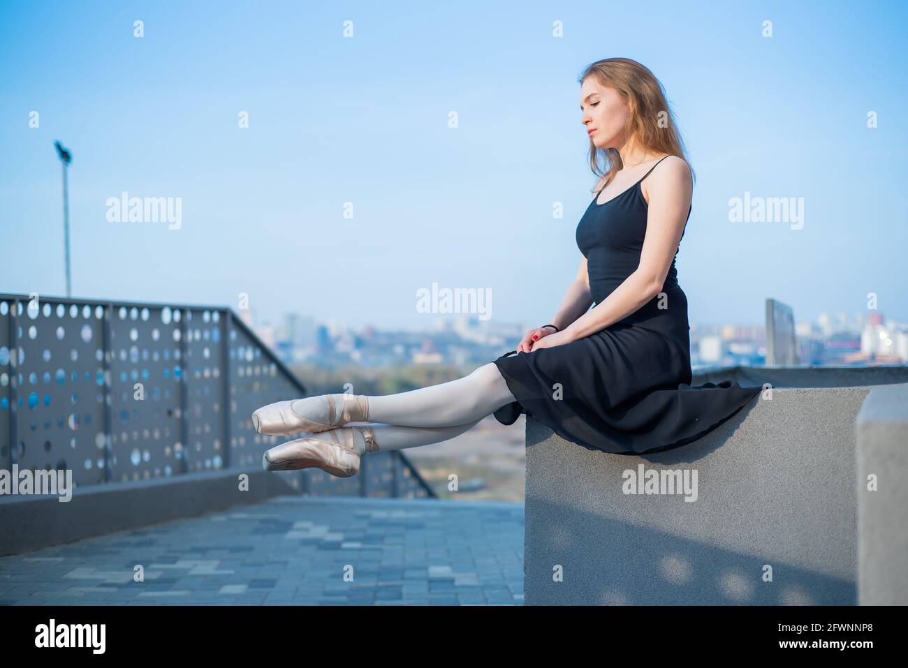 Ballerina in tutu posing sitting. Beautiful young woman in black dress ...